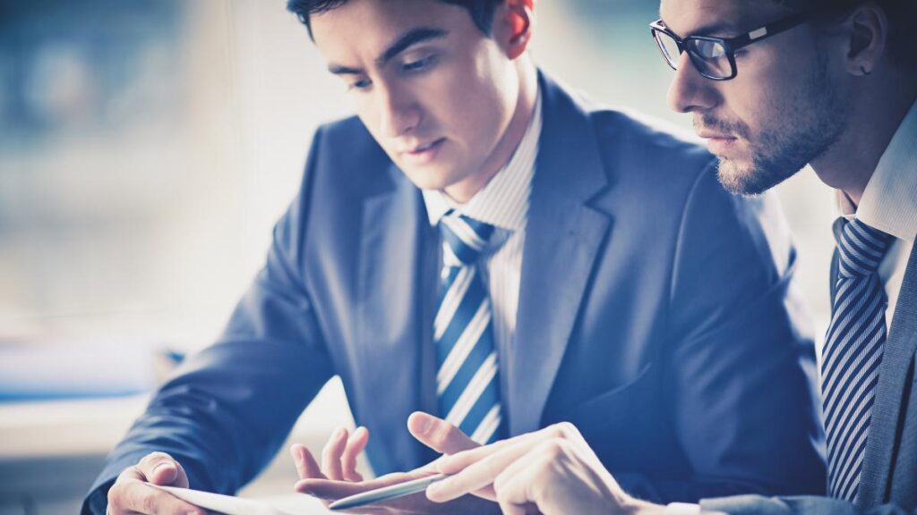 Dois homens de terno olhando para um tablet